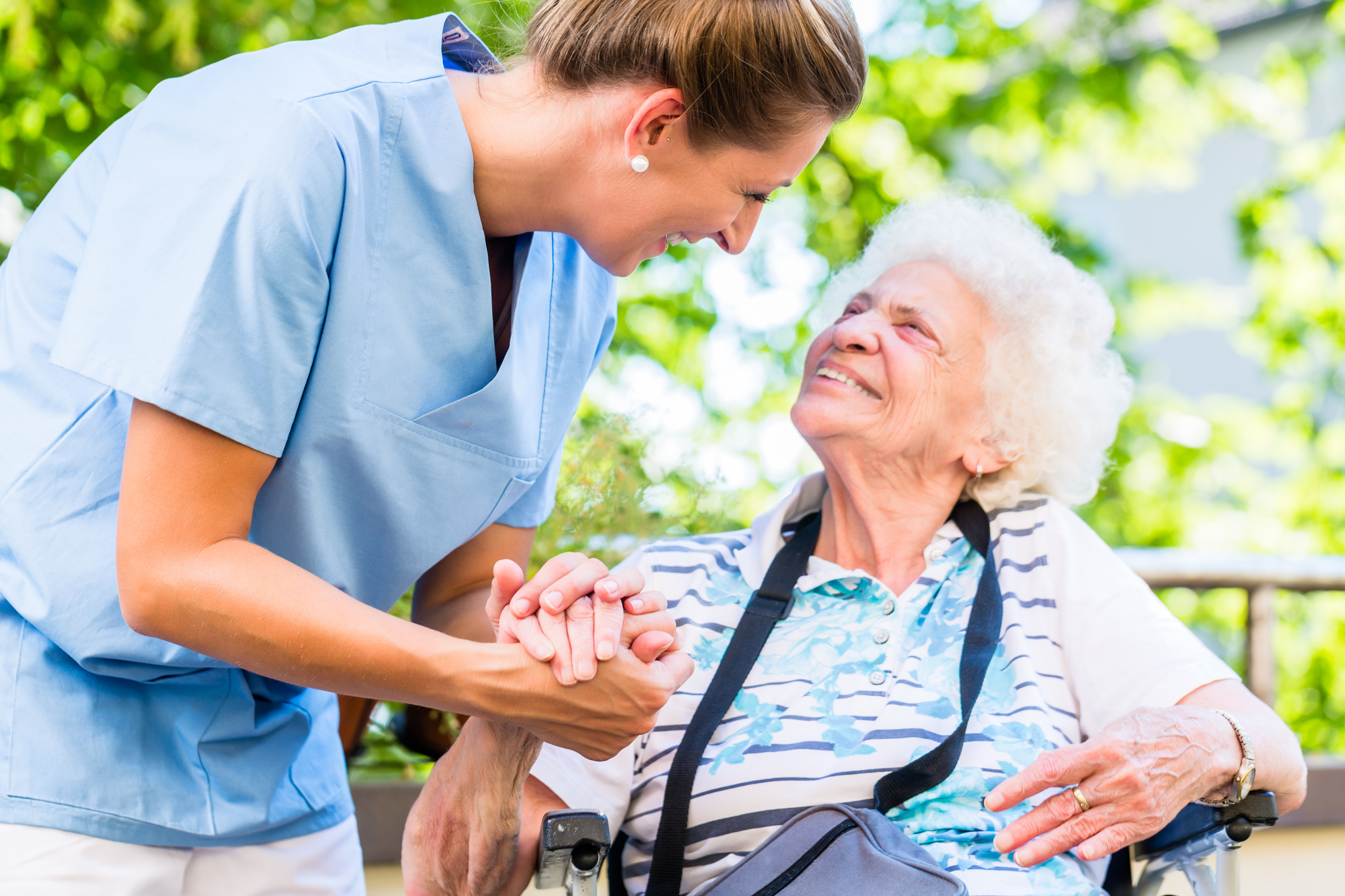 Nurse holding hand of senior woman in home