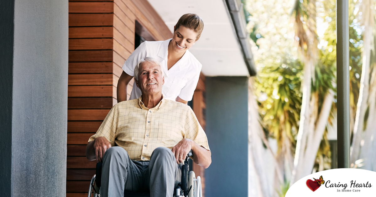 A caregiver brings an elderly man in a wheelchair out of a building, demonstrating a hospital discharge.