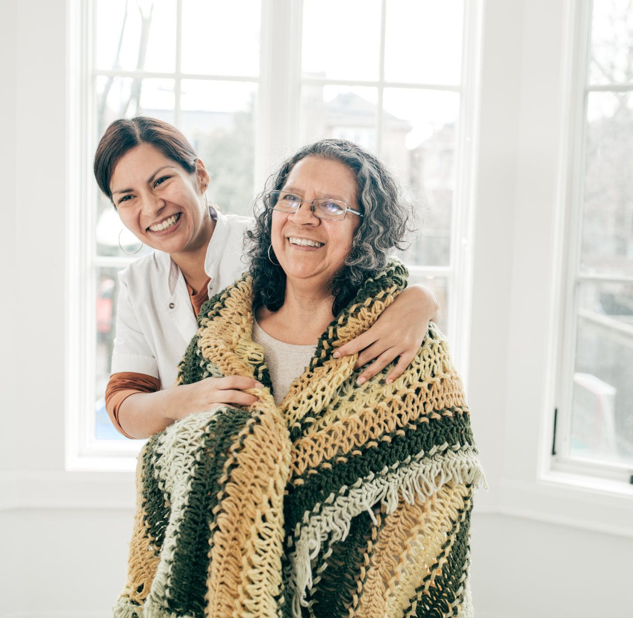 A caregiver wrapping a senior client in a blanket represents Premier Private Care in Prescott