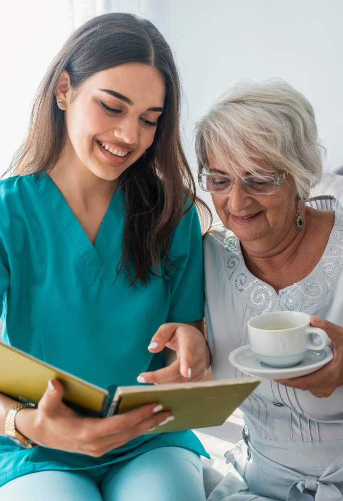 A caregiver shows a notebook to a client having something to drink.