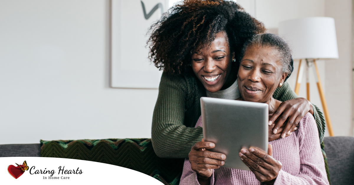 A caregiver helps a senior with her tablet, representing the rise of technology in home care.