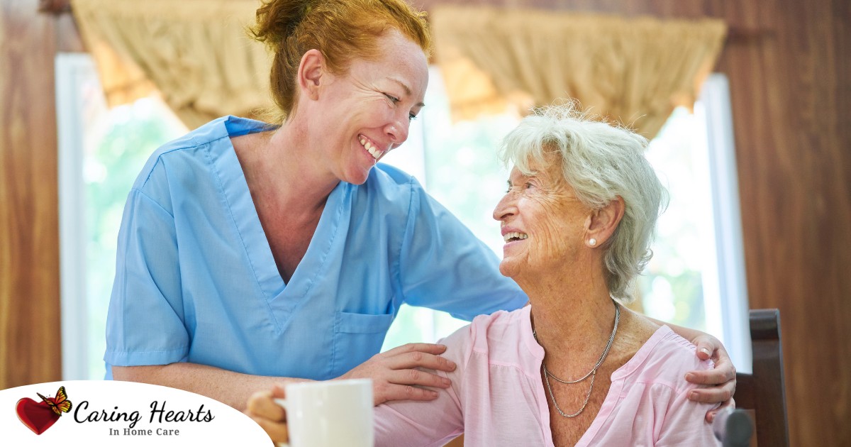 A caregiver and client smile while the caregiver hugs and helps the client, representing professional caregiving.