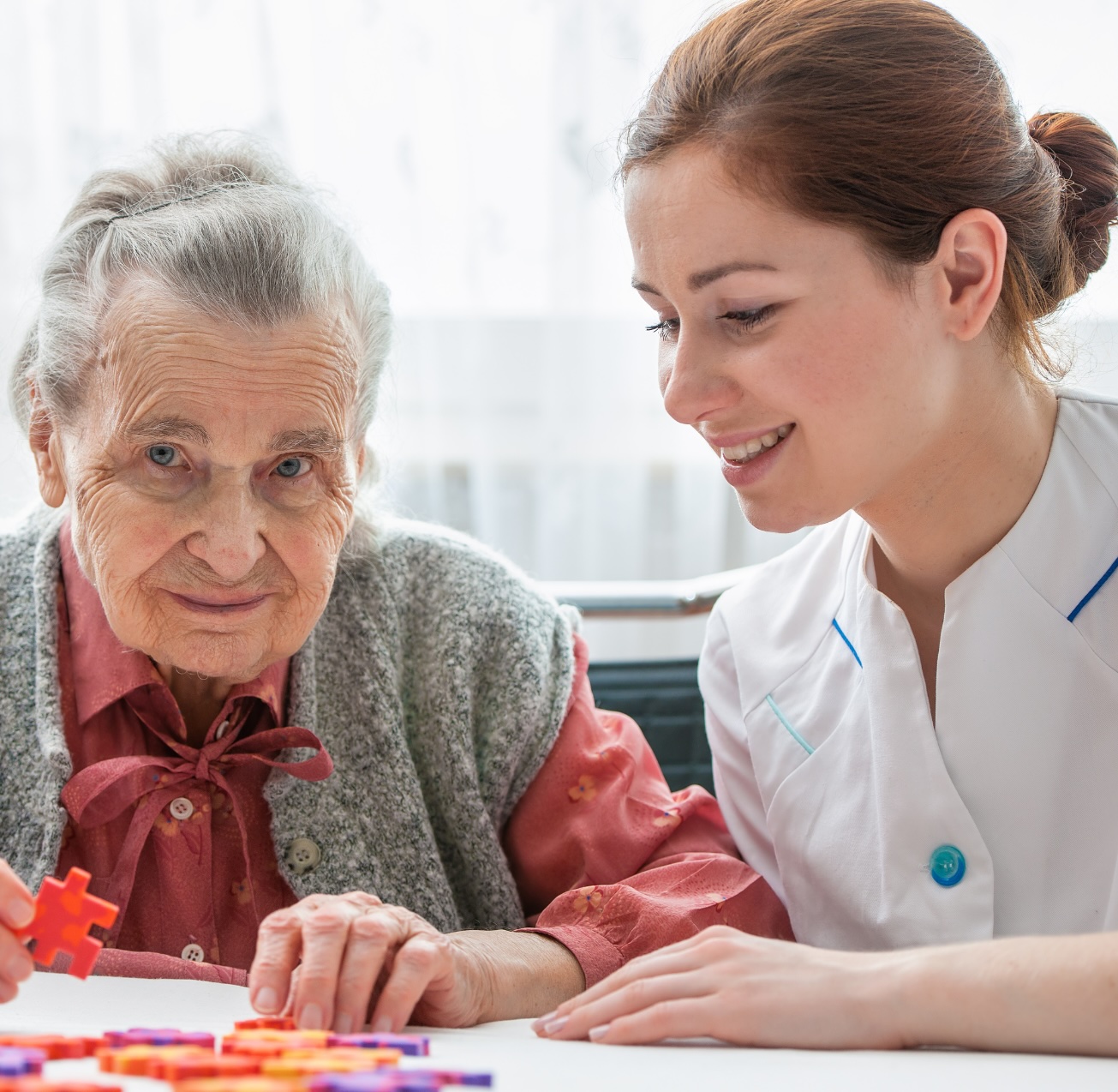 Specialized Care A caregiver helps a client with a puzzle representing specialized care in Prescott