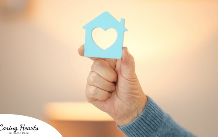 A hand holds up a cutout of a home with a heart in it, representing the home care industry.