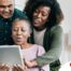 A daughter looks at a tablet with her older parents, representing technology and how ti can help with aging in place.