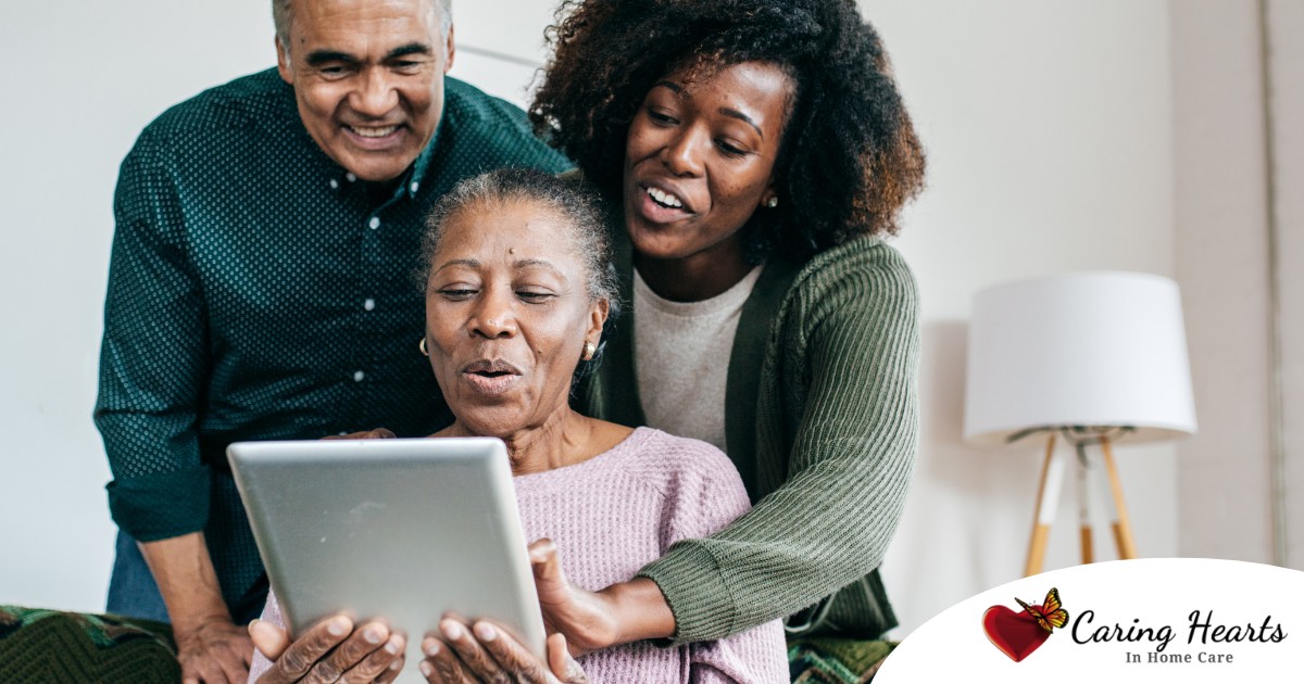 A daughter looks at a tablet with her older parents, representing technology and how ti can help with aging in place.
