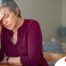 A woman holds her head in her hand, representing the stress that new family caregivers go through.