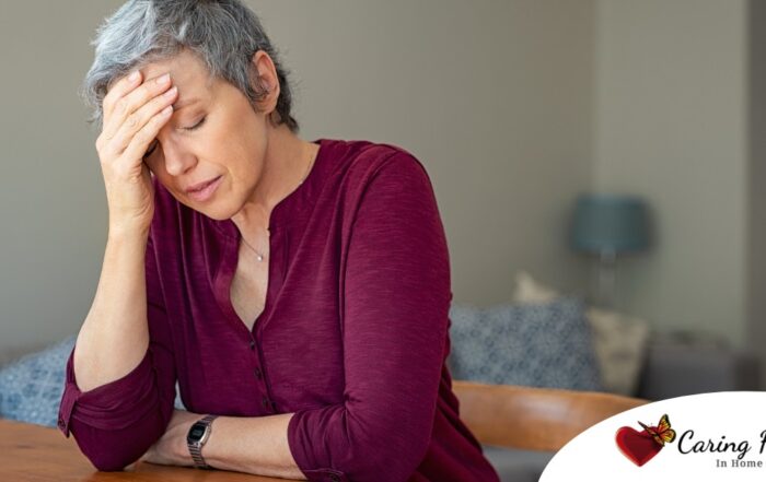 A woman holds her head in her hand, representing the stress that new family caregivers go through.