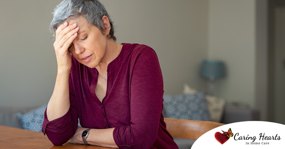 A woman holds her head in her hand, representing the stress that new family caregivers go through.
