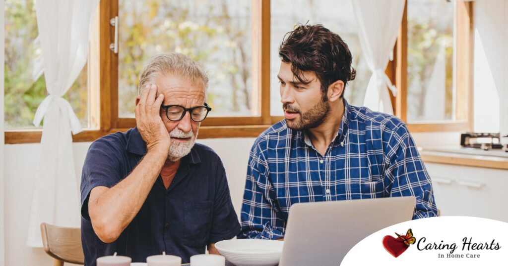 A man looks at a computer with his father who is confused, representing one of the early signs of dementia.