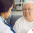 A doctor examines an older man with a stethoscope, representing pneumonia in elderly adults.